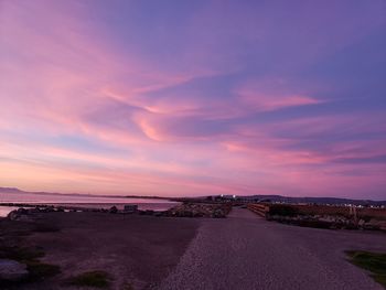 Road by sea against sky during sunset