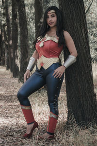 Full length portrait of woman on tree trunk in forest