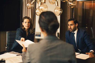 Mid adult lawyer with colleague giving document to advisor in office