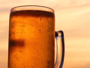 Close-up of beer glass against orange background