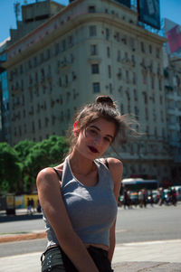 Young woman with umbrella on road in city