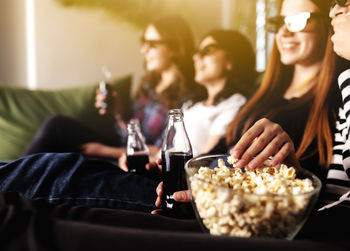 Group of people are watching a movie. friend girls eat popcorn and drink soda