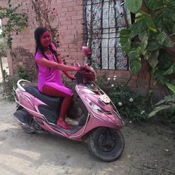 Side view of woman sitting on pink motorcycle