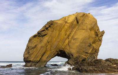 Rock formation on beach against sky