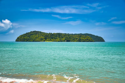 Waves of the azure andaman sea under blue sky reaching the shores of the sandy exotic cenang beach