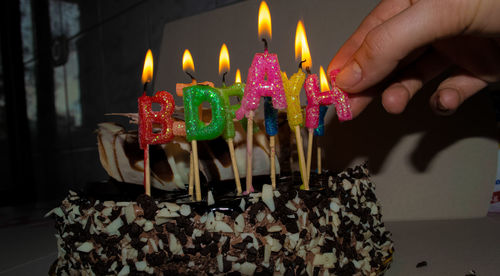 Cropped image of person holding burning birthday candle on cake
