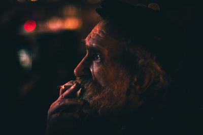 Close-up of senior man smoking cigarette at night