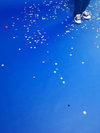Low section of man with balloons in blue background