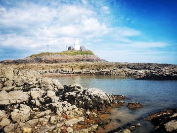 Lighthouse by sea against sky