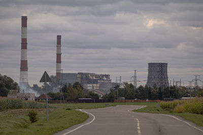 Road by factory against sky in city