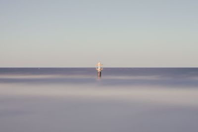 Man standing in sea against clear sky