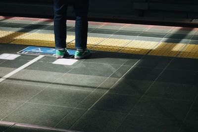 Low section of person standing on tiled floor