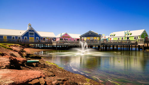 Houses by water against clear blue sky