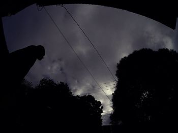 Low angle view of silhouette trees against cloudy sky