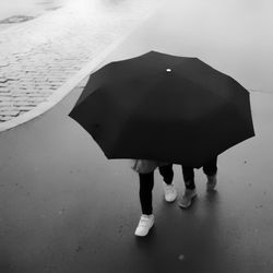 Low section of woman standing on umbrella