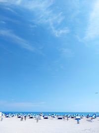 Group of people on beach against blue sky