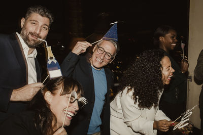 Cheerful business people with props enjoying company party at night