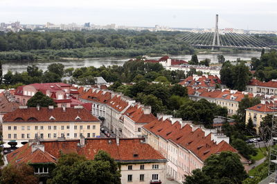 Town with swietokrzyski suspension bridge over vistula river against sky