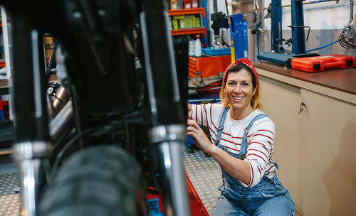 Portrait of mechanic woman repairing motorcycle on factory