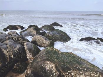 Scenic view of rocks on beach against sky