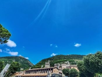 Panoramic view of buildings and trees against blue sky