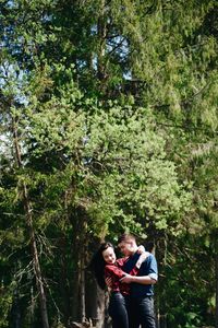 Loving young couple standing against trees in forest