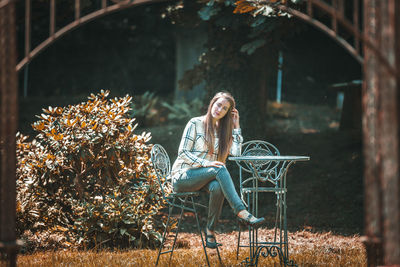 Full length of woman sitting on chair in park