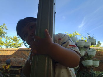 Low angle view of girl looking away against sky