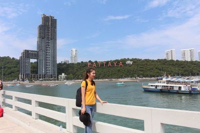 Full length of woman standing by railing against buildings in city