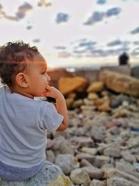 Cute boy looking away on rock