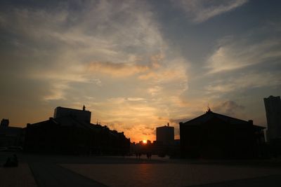 Modern city against sky during sunset