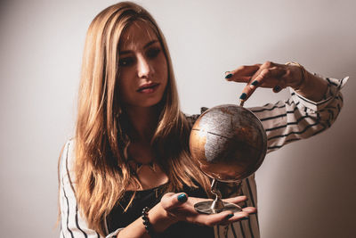 Woman looking at globe against gray background