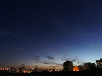 Illuminated cityscape against blue sky at night