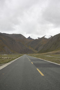 Empty road by mountains against sky