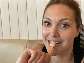 Close-up portrait of a smiling young woman holding ice cream