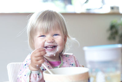 Cheerful cute girl eating ice cream at home