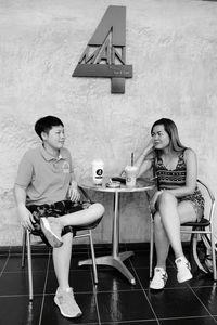 Full length of young couple sitting on chair