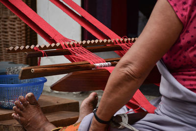 Low section of woman weaving on loom