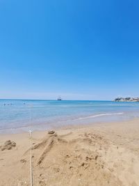 Scenic view of beach against clear blue sky