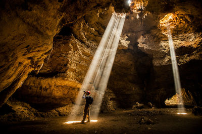 Side view of man photographing while standing in caves