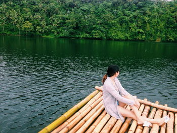 Rear view of woman sitting on lake