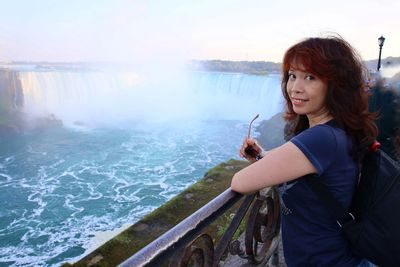 Woman standing by railing against water