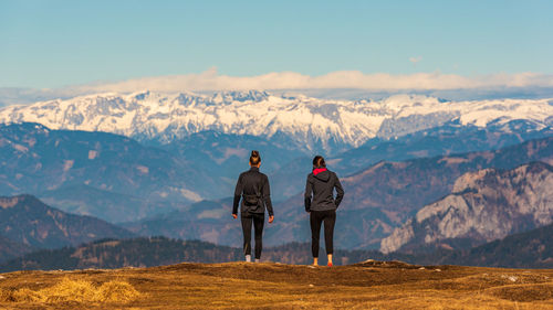 Rear view of men standing on mountain against sky