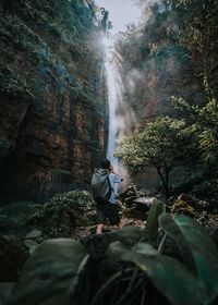 Side view of man on rock in forest