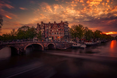 Arch bridge over river against sky during sunset