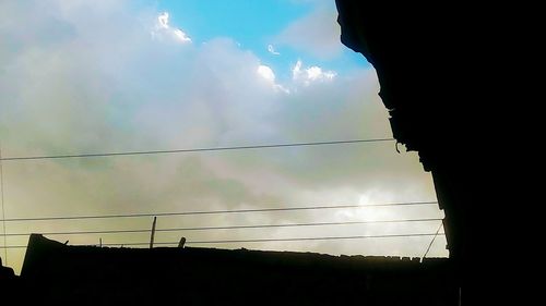 Low angle view of silhouette electricity pylon against sky