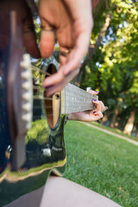 Close-up of woman playing guitar at public park