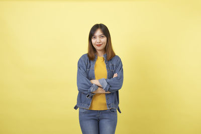 Portrait of smiling young woman against yellow background