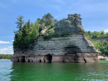 Rock formation by sea against sky