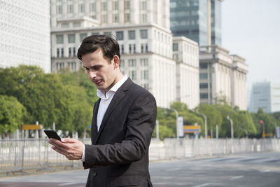 Young businessman using mobile phone in city